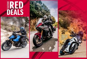 Drei Suzuki-Motorräder nebeneinander, links ein blaues Naked Bike, in der Mitte ein rot-graues Tourenmotorrad mit zwei Fahrern, rechts ein weißes Sportmotorrad, dazu das Logo „Suzuki Red Deals“.